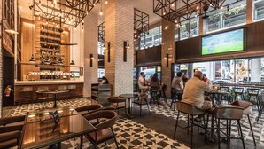 A modern bar area with a checkered floor, bar stools, and a large screen displaying a sports game. - Holiday Inn Bangkok by IHG (Bangkok)