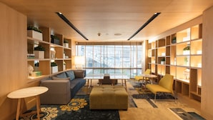 A modern library with wooden bookshelves, a sofa, a table, and a patterned rug.