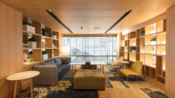 Eine moderne Bibliothek mit Holzbögen, einem Sofa, einem Tisch und einem gemusterten Teppich.