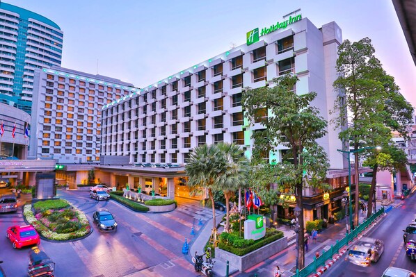 Un hôtel Holiday Inn au design moderne, doté d’une cour intérieure avec des palmiers et d’un rond-point pour la circulation.