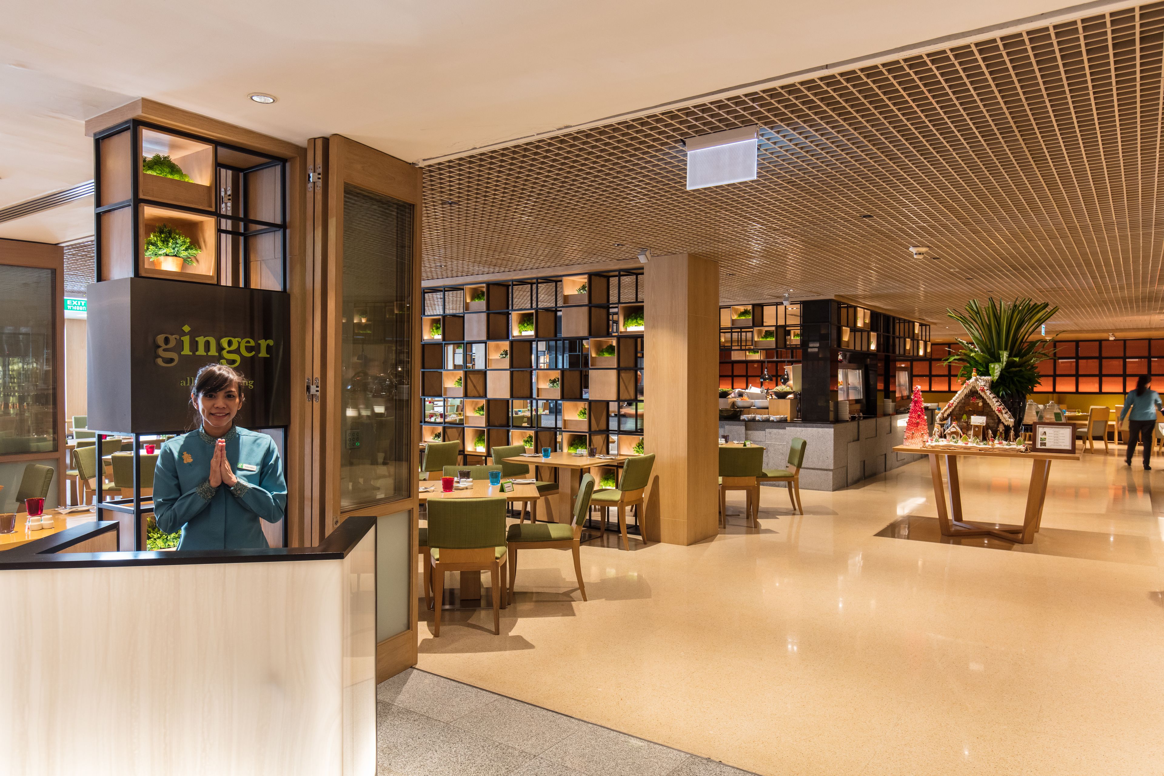 A modern hotel lobby with a reception desk, seating areas, and a variety of plants and greenery.