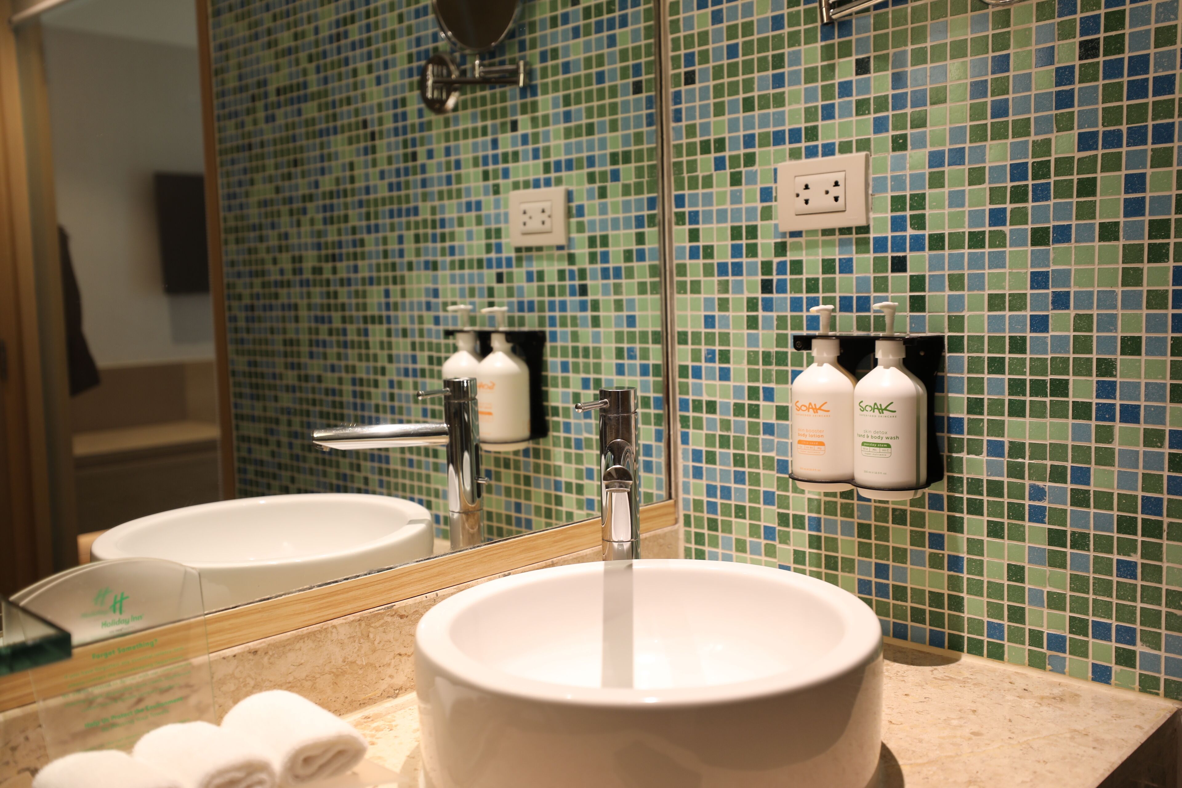 A bathroom with a white sink, a mirror, and two soap dispensers on the wall.