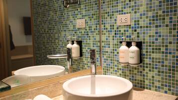 A bathroom with a white sink, a mirror, and two soap dispensers on the wall.