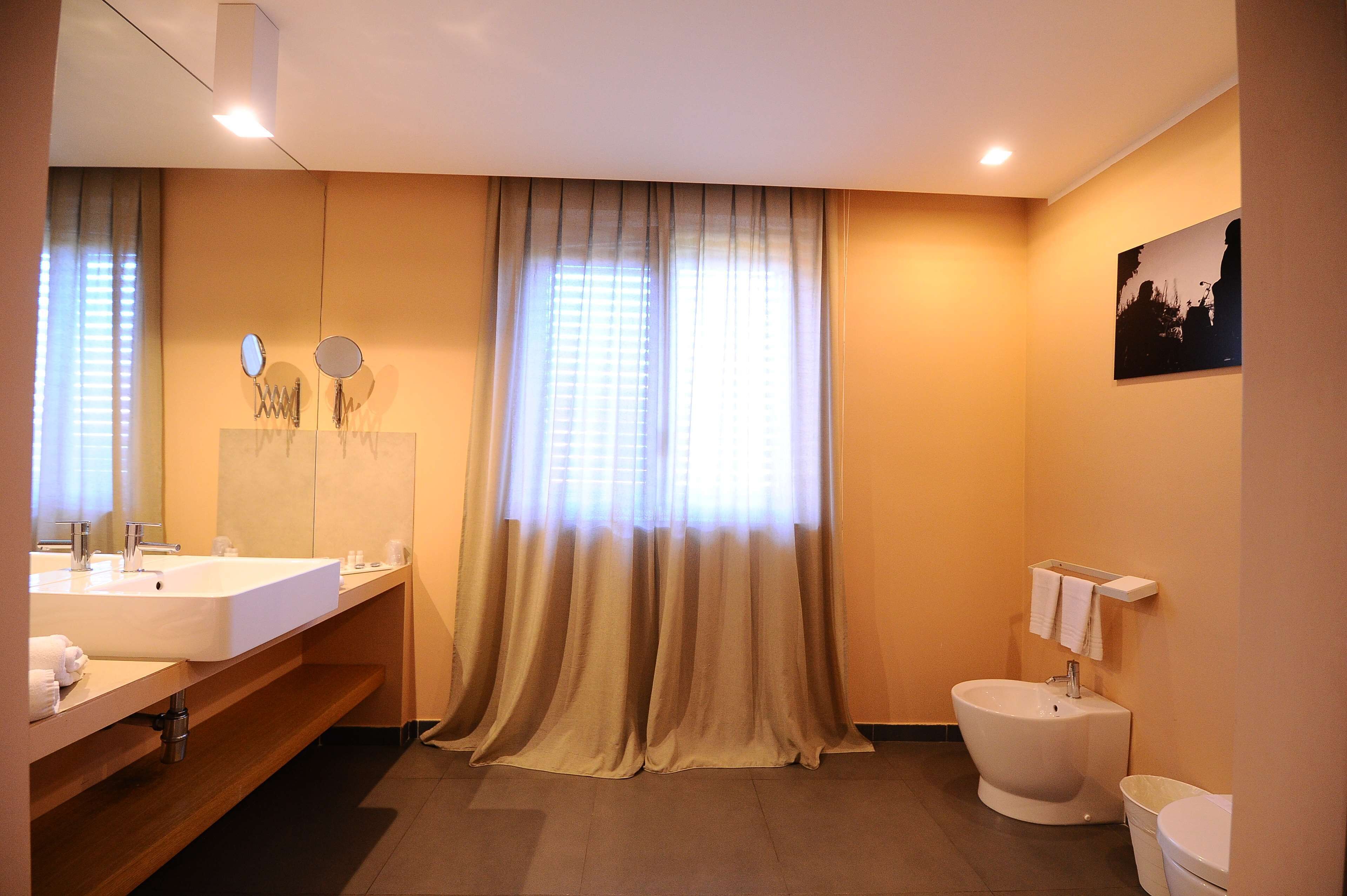 Un bagno con lavandino, specchio, mobile e water.