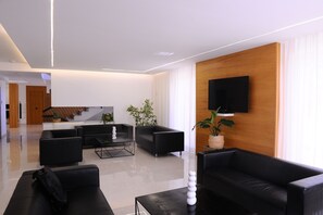 Relax in a stylish living room with a flat-screen TV, comfortable seating areas, and a polished floor.