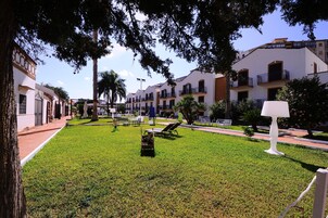 Un cortile con prato, lettini e un lampione.