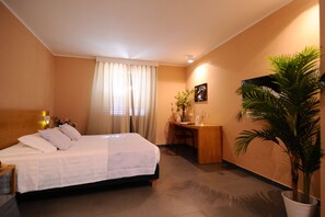 Comfortable room with a neatly made bed, desk, and potted plant.