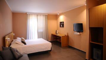 A hotel room with a bed, a desk, a television, and a wardrobe.