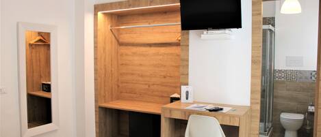 A modern bathroom with a wooden shower enclosure, a mounted TV, and a small desk with a chair.