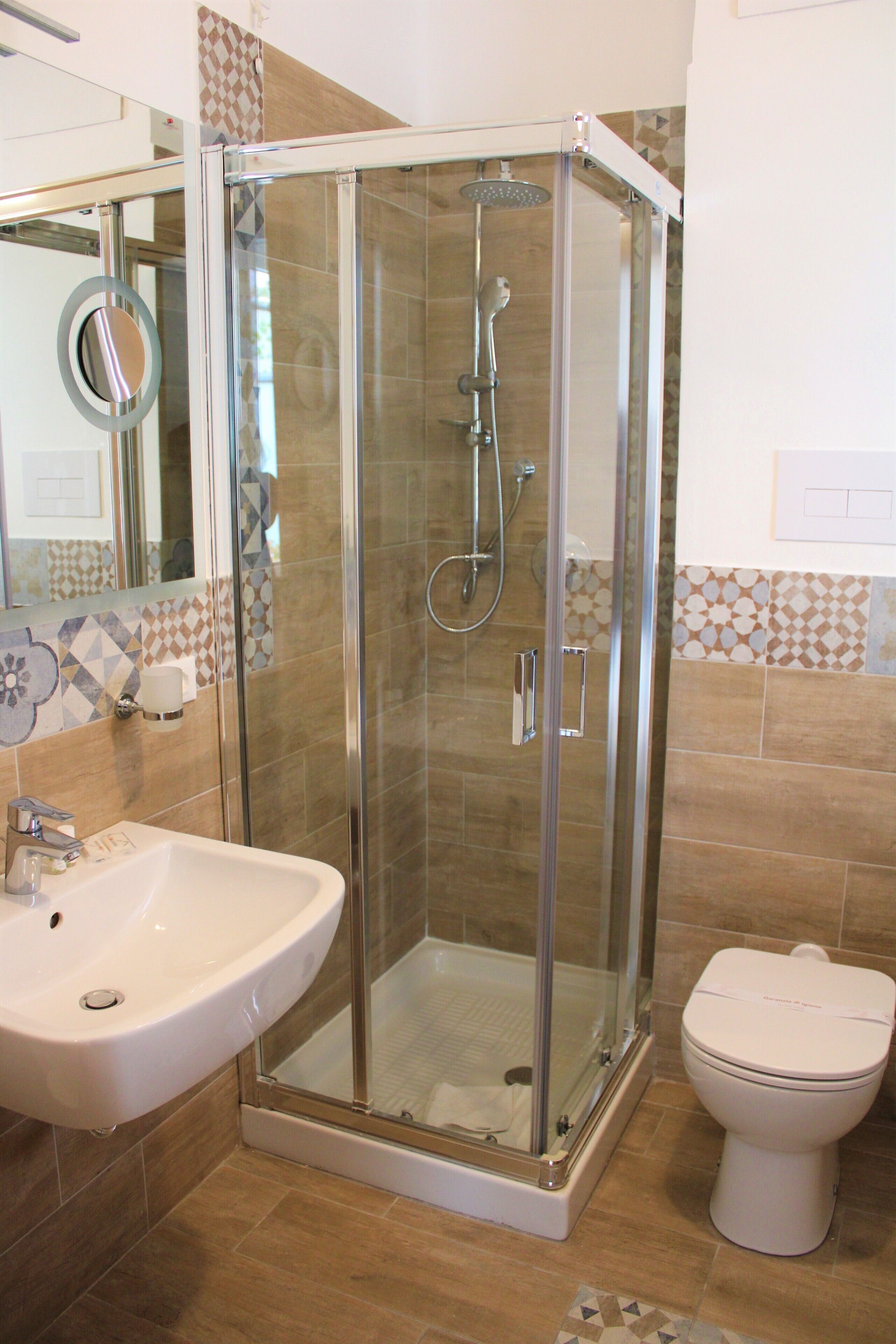 A bathroom with a glass-enclosed shower, a sink, and a toilet.