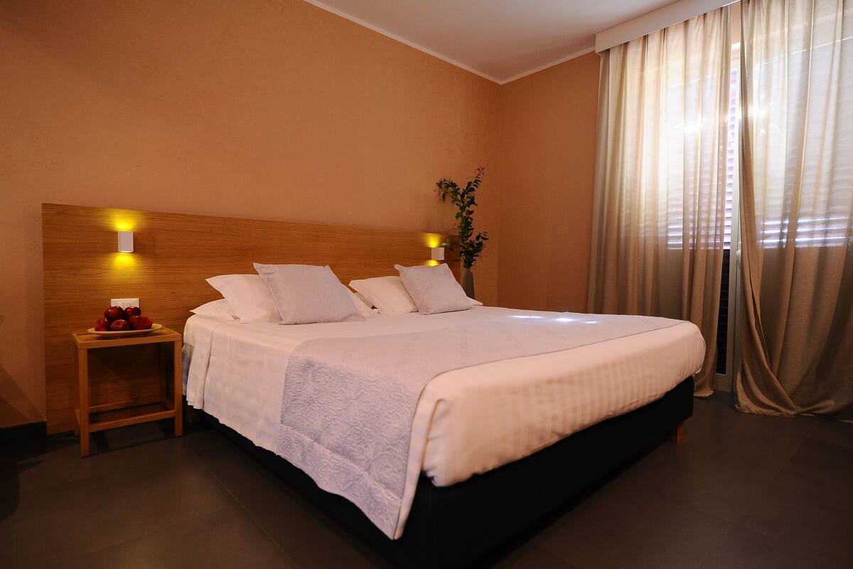 A neatly made bed with white linens, a wooden headboard, and bedside lamps.