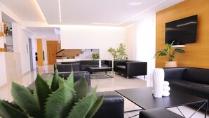 A modern living room with a black sofa, a coffee table, and a TV mounted on the wall. There is a staircase leading to another level. - Casena Dei Colli, Sure Hotel Collection by Best Western (Palermo)