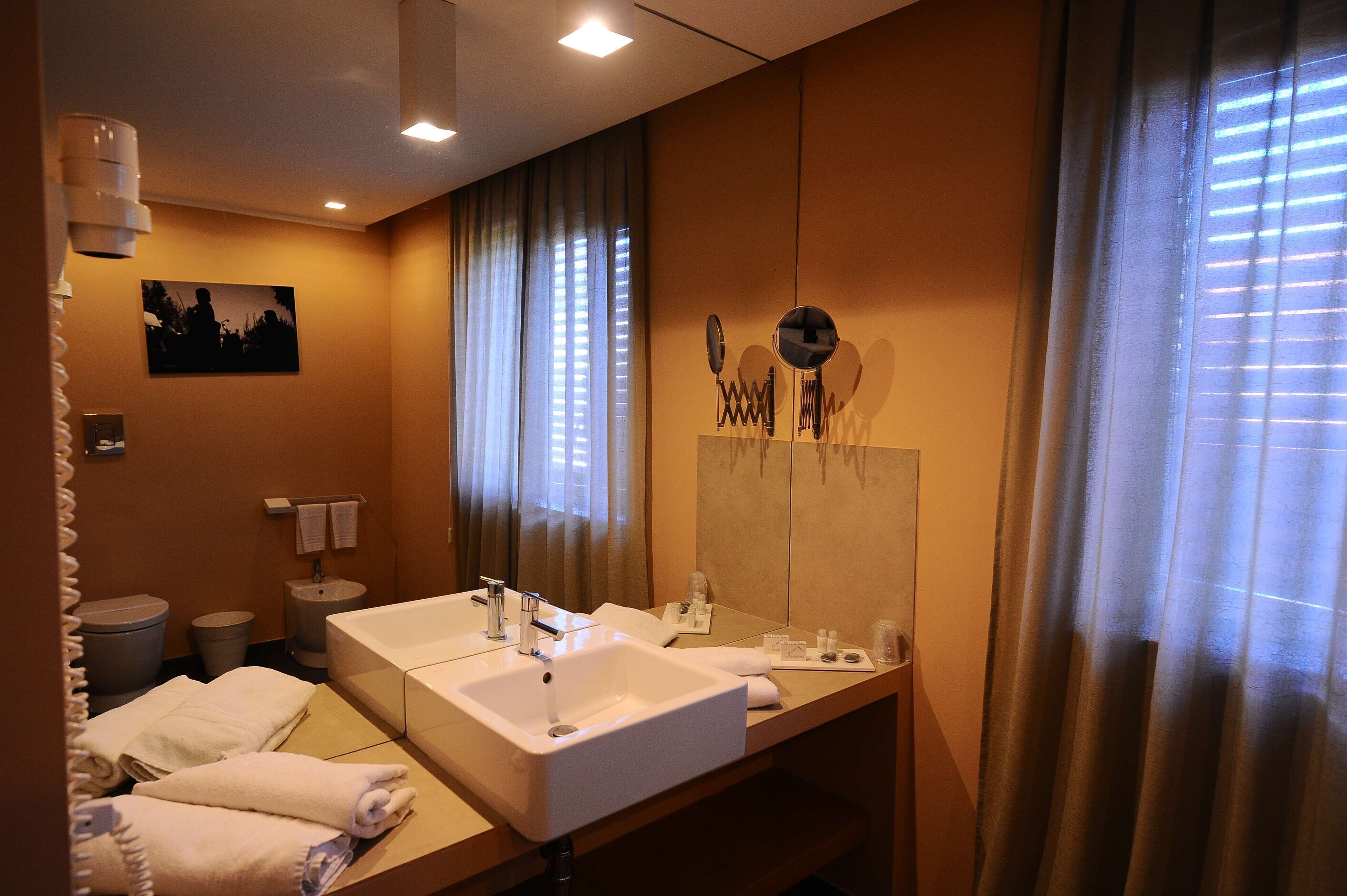 A hotel bathroom with two sinks, a mirror, and a towel rack.