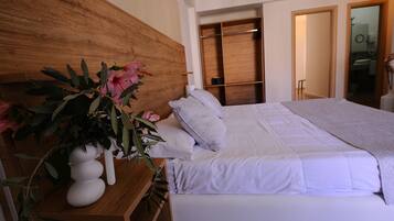 Camera da letto con una testiera in legno, un letto con biancheria bianca, un comodino con un vaso di fiori e un armadio in legno.