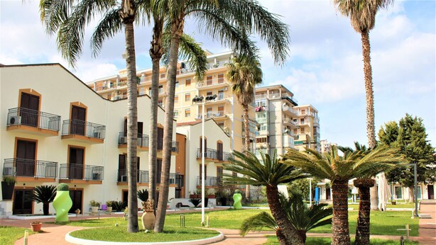 A multi-story hotel with balconies, palm trees, and a well-maintained garden. - Casena Dei Colli, Sure Hotel Collection by Best Western (Palermo)
