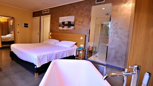 A hotel room with a large bed, a separate bathroom with a bathtub, and a mirror reflecting the room. - Casena Dei Colli, Sure Hotel Collection by Best Western (Palermo)