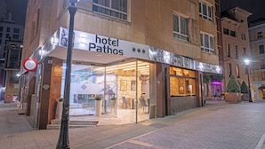 Un hôtel appelé « hôtel Pathos », doté d’une façade en verre, d’un espace extérieur aménagé pour les clients et d’une enseigne indiquant un classement de trois étoiles.