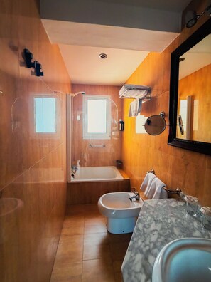 Une salle de bain compacte comprenant une baignoire, un bidet et un lavabo.