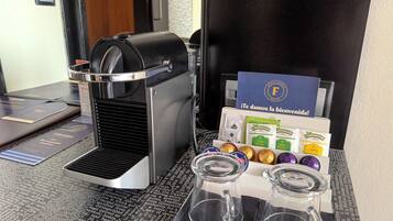 Uma máquina de café, um letreiro com uma mensagem de boas-vindas e uma seleção de cápsulas de café.
