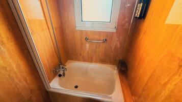 Ein kleines Badezimmer mit Holzoptik, einer Badewanne, einem Fenster und einem Handtuchhalter.