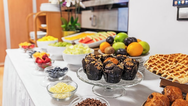 Une table de buffet proposant divers plats, notamment des fruits, des pâtisseries et des gaufres.