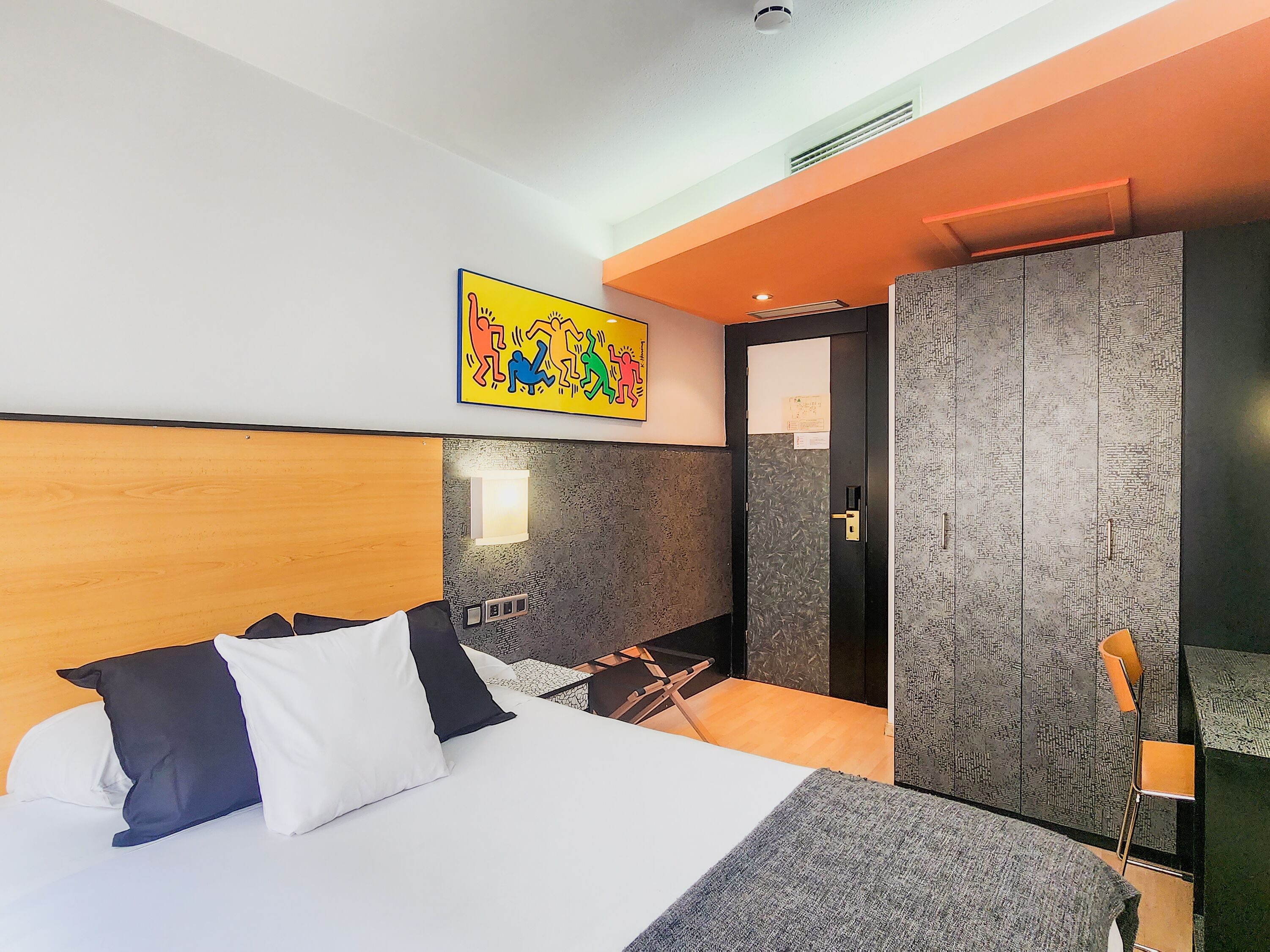 Een hotelkamer met een bed, een kast, een tafeltje en een stoel.