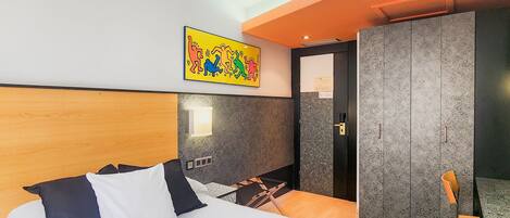 Een hotelkamer met een bed, een kast, een tafeltje en een stoel.