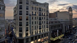 A multi-story hotel with a classic architectural design, featuring balconies and a prominent hotel sign. - Hotel Regente (Madrid)