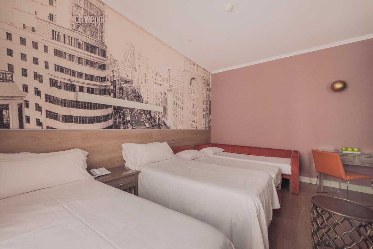 Une chambre d’hôtel avec deux lits, un bureau, une chaise et une fresque murale.