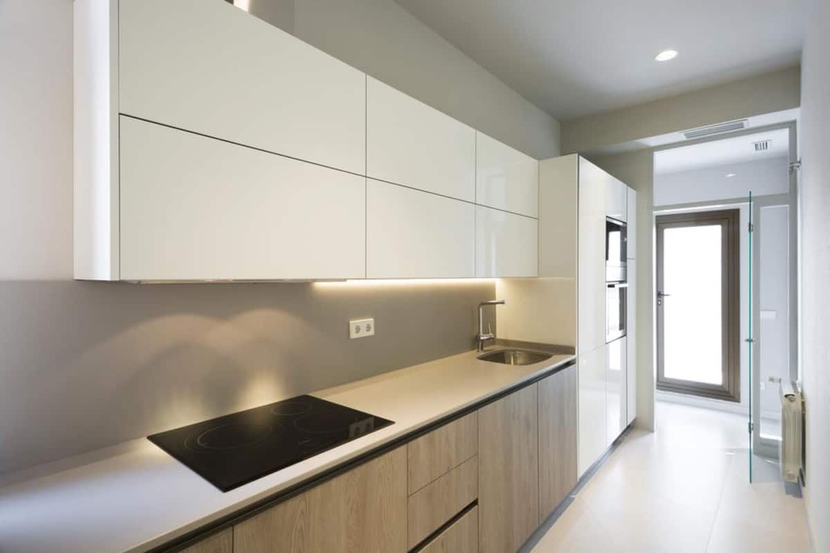 Une cuisine moderne dotée d’une cuisinière intégrée, d’un évier et de meubles de rangement de couleur claire.