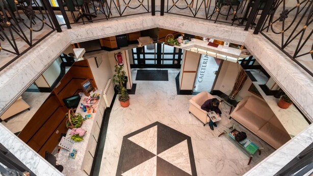 A spacious lobby with a geometric floor design, a reception desk, seating area, and a visible staircase. - Hotel Astures (Oviedo)