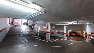 A multi-level parking garage with concrete walls, red and white striped barriers, and clear directional markings on the floor.