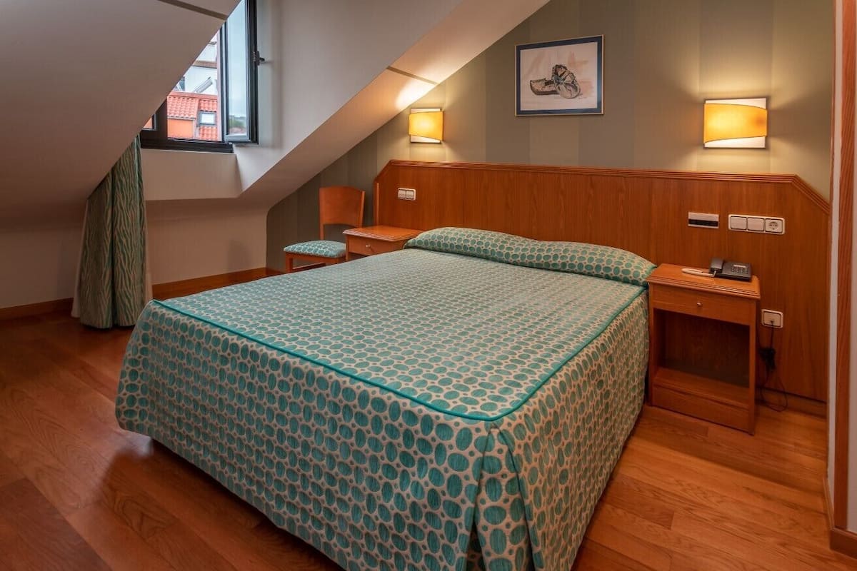 A bedroom with a large bed, wooden headboard, bedside tables, and a window.
