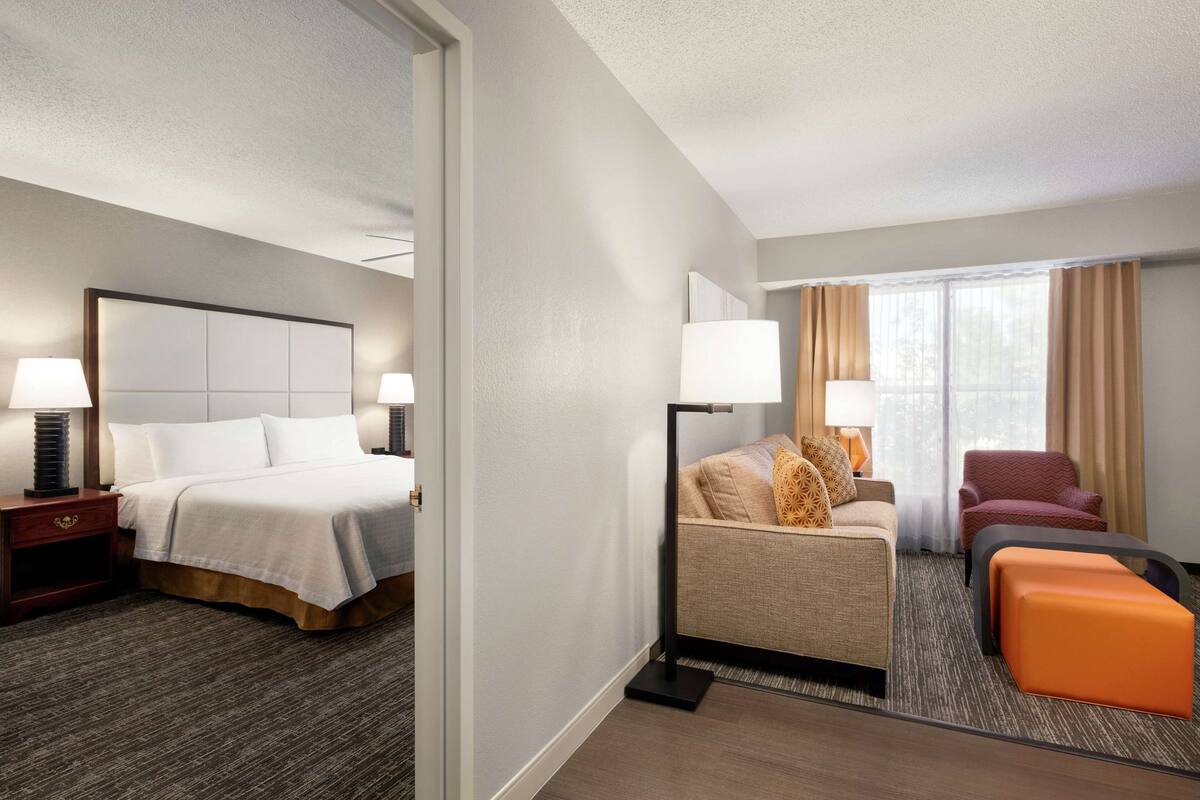 Een hotelkamer met een bed, nachtkastjes, een bank, een poef en een stoel.
