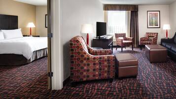 A hotel room with a bed, two armchairs, a sofa, a TV, and a desk.