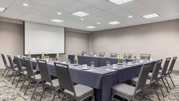 A conference room with a long table, chairs, and a projector screen.