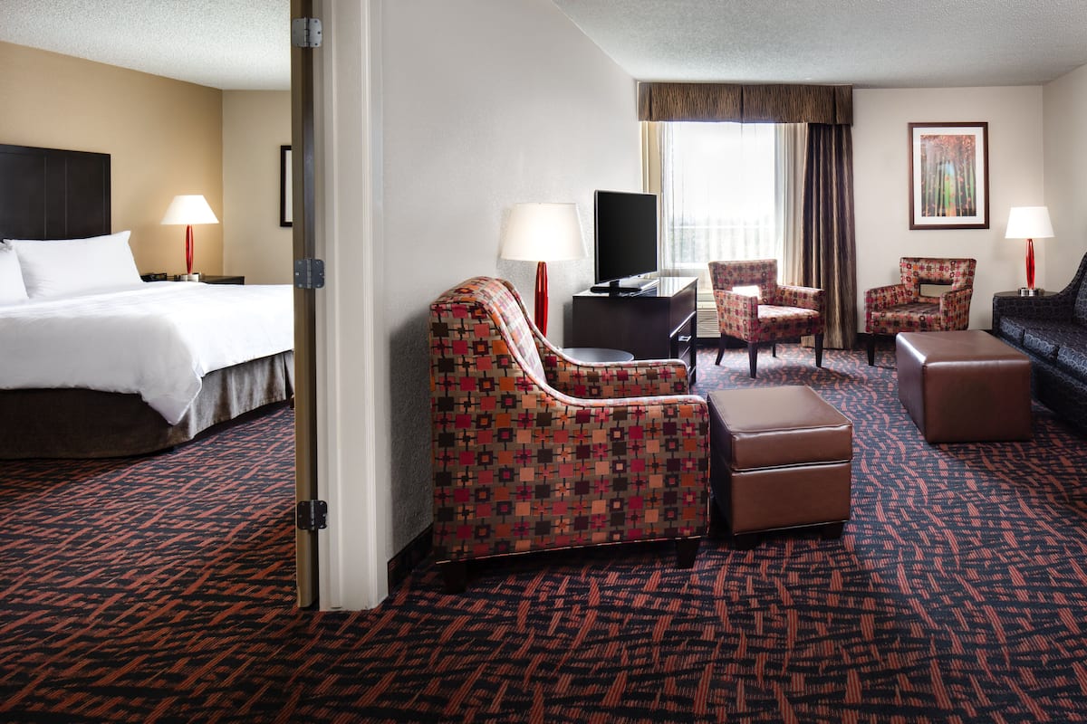 A hotel room with a bed, a TV, two armchairs, a sofa, and a small table.