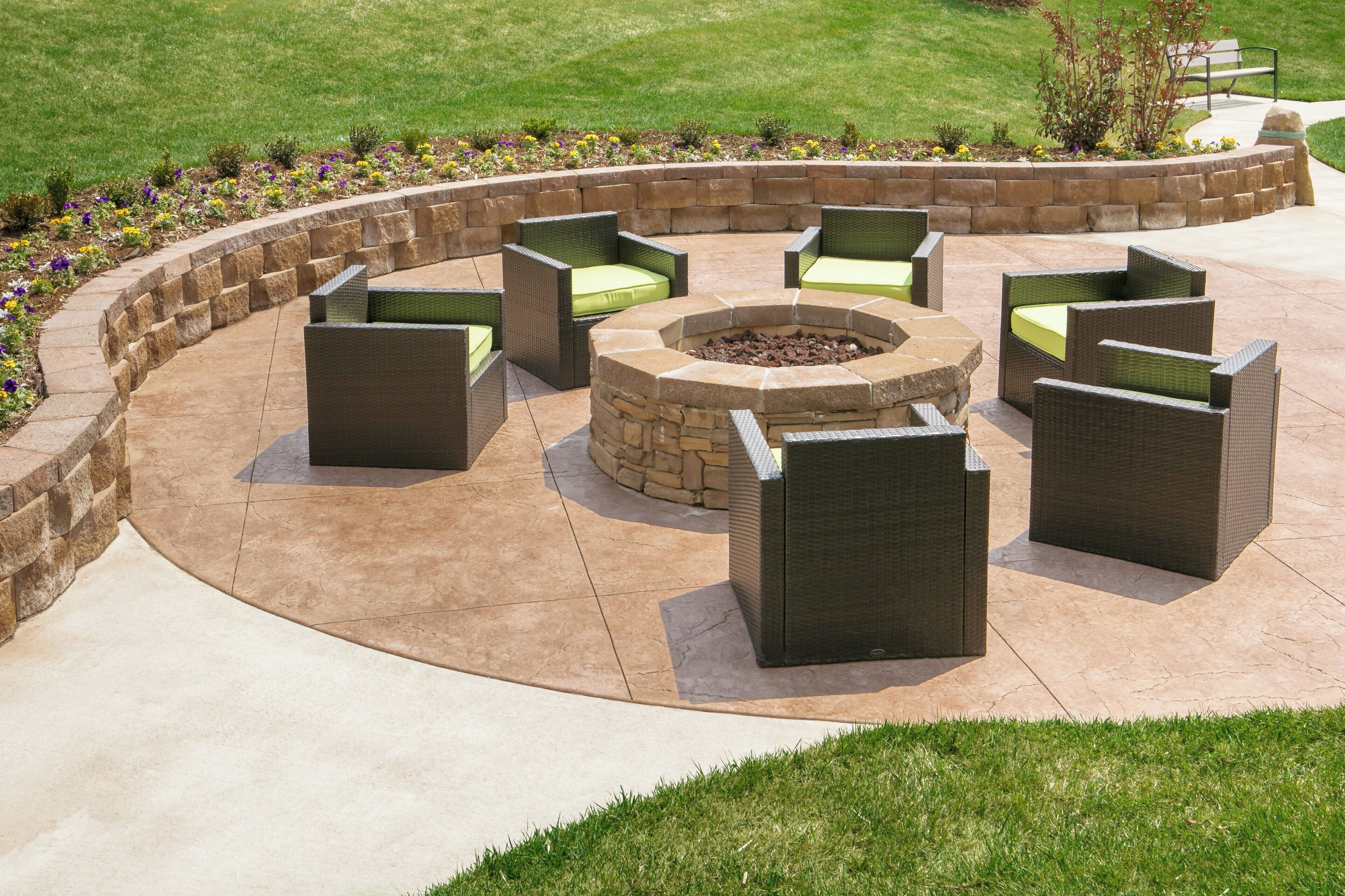 A circular outdoor seating area with wicker furniture and a stone fire pit.