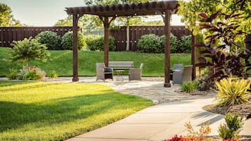 A patio area with a pergola, a bench, and a table.