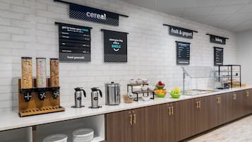 Un buffet pour le petit-déjeuner proposant des céréales, des fruits et des yaourts, ainsi qu’un choix de produits de boulangerie.