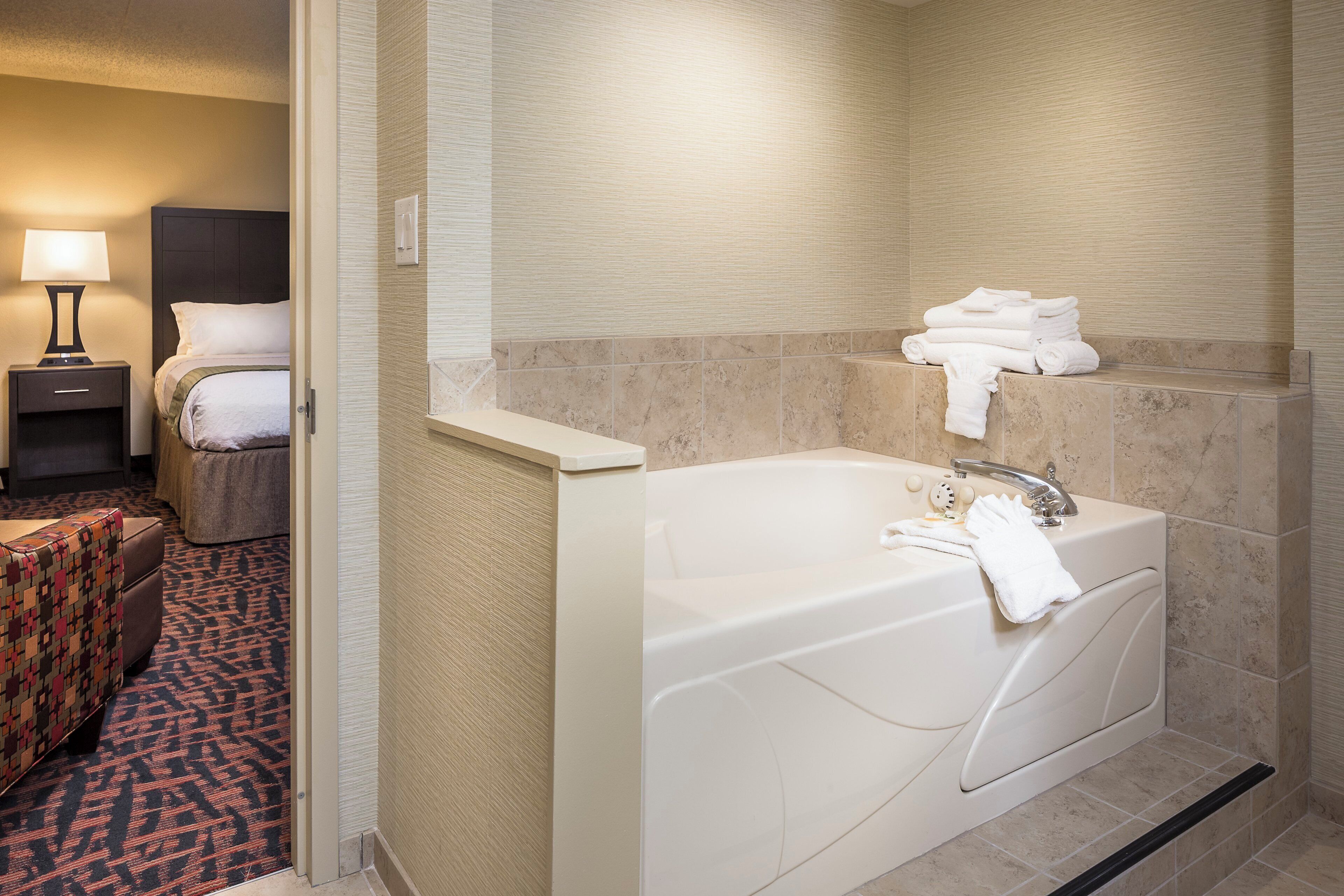 Ein Hotelbad mit einer Badewanne, einem Handtuchhalter und einem Nachttisch mit einer Lampe.