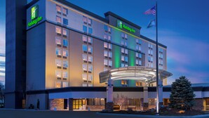 A Holiday Inn hotel with a modern design, featuring a prominent American flag and a well-lit entrance. - Holiday Inn Wichita East I-35 by IHG (Wichita)