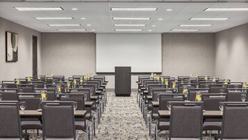 A conference room with rows of chairs, a projector screen, and a podium.