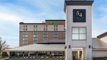 A Holiday Inn hotel with a modern design, including a prominent number 54 sign, a covered entrance, and a parking area with handicapped accessibility signs.