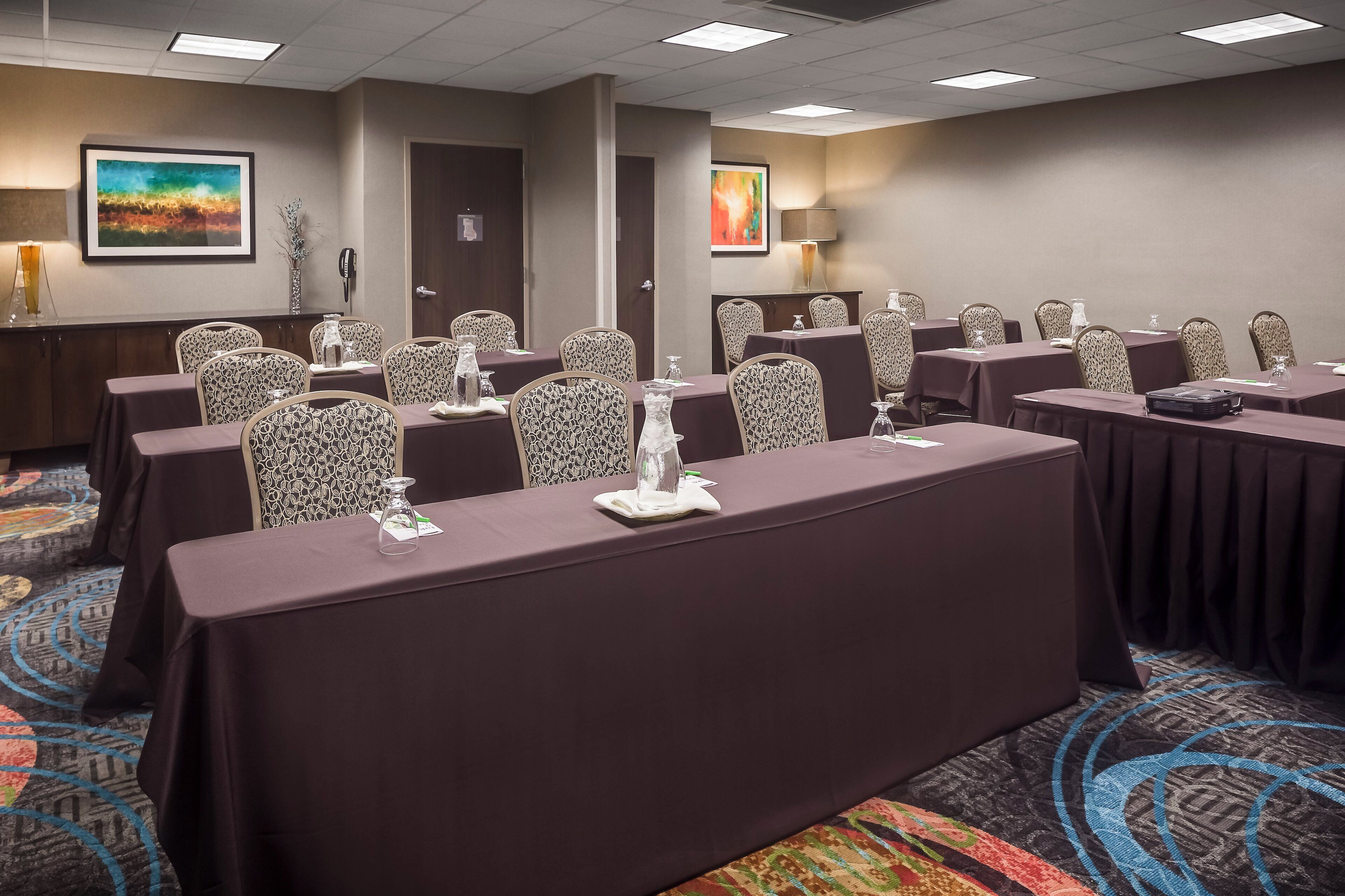 A conference room with multiple tables, chairs, and a carpeted floor.