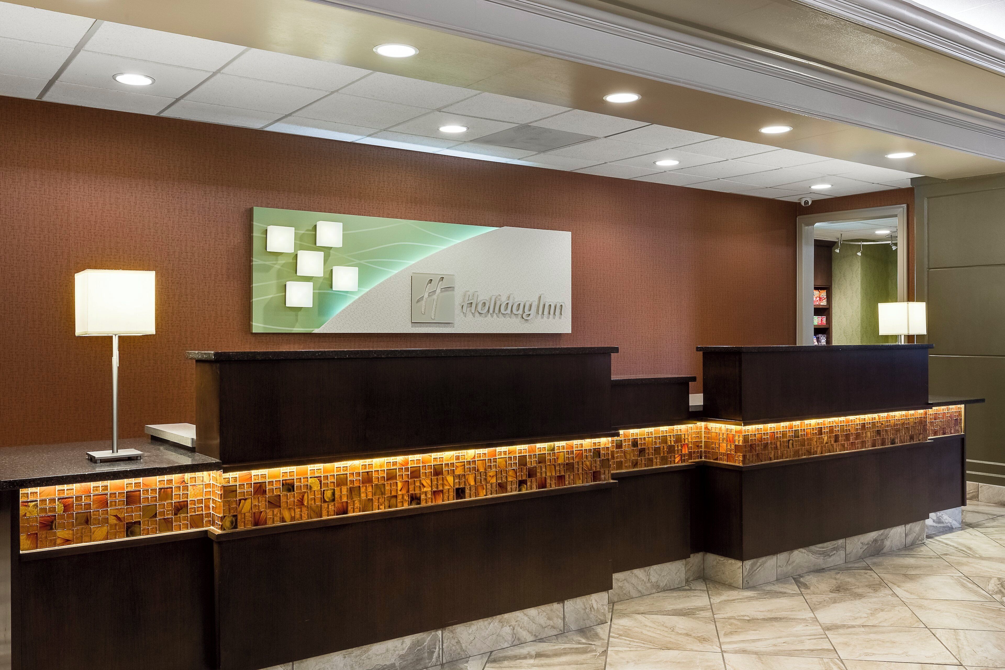 A reception desk with a modern design, a wall-mounted sign, and a patterned tile backsplash.