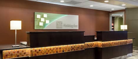 A reception desk with a modern design, a wall-mounted sign, and a patterned tile backsplash.