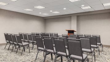 Uma sala de conferência com fileiras de cadeiras, um púlpito e piso coberto de carpete.
