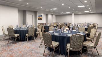 A conference room with round tables, patterned chairs, and a carpeted floor.
