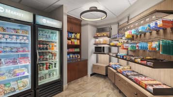 A grocery store interior with refrigerated sections, shelves stocked with snacks, and a microwave.